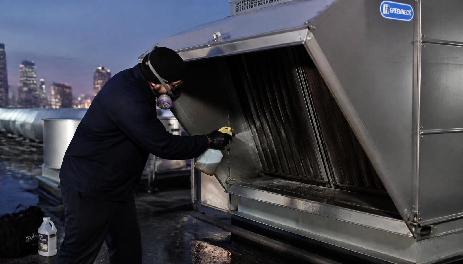 Rooftop commercial kitchen exhaust fan tilted open on its hinge kit for degreasing