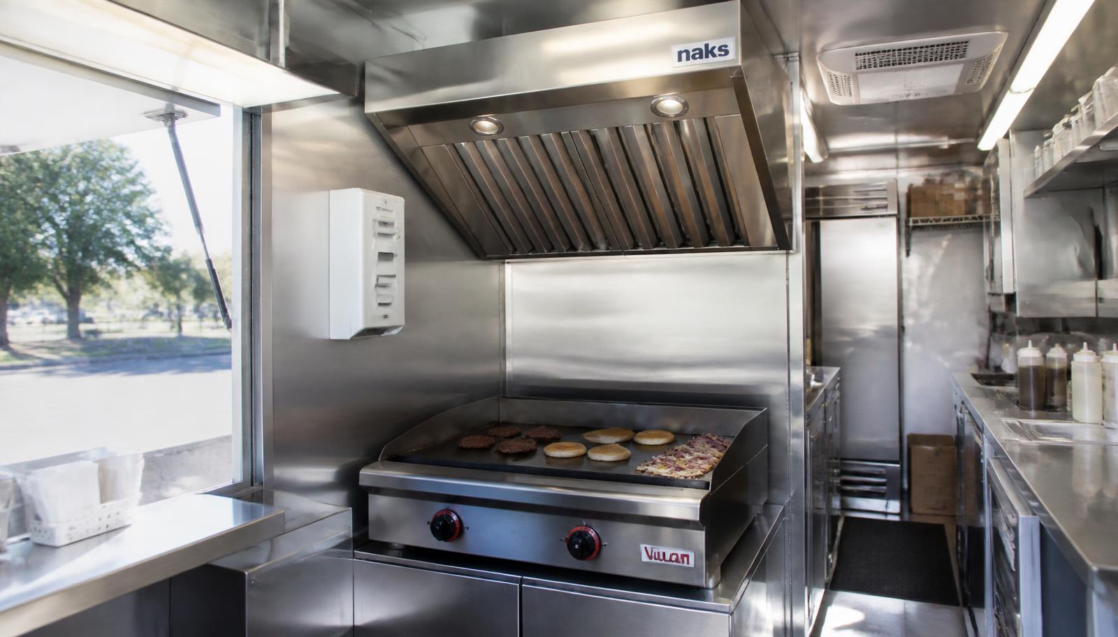 Food truck kitchen with a compact stainless exhaust hood above the griddle